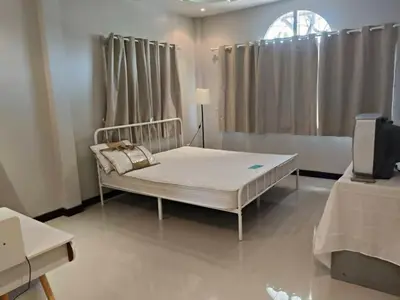 a bedroom with a white bed and a television at Joyful House3 in Thalang