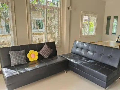 a black leather couch in a living room with windows at Joyful House3 in Thalang