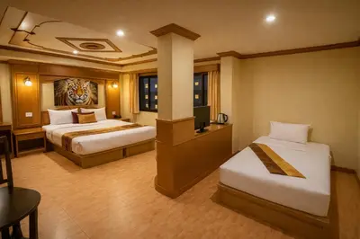a hotel room with two beds and a television at Tiger Complex Suites in Patong Beach