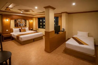 a hotel room with two beds and a television at Tiger Complex Suites in Patong Beach