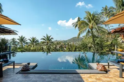 a pool at a resort with two people laying on the floor at Arun Rapee Villa Surin Beach in Surin Beach