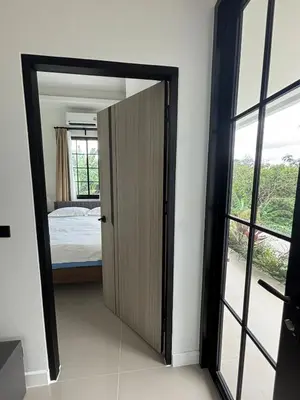 a door leading to a bedroom with a bed at Natureville cozy home near Samet Nangshe