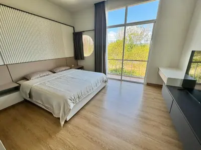 a bedroom with a bed and a large window at Modern townhome in Phuket in Ban Phak Chit