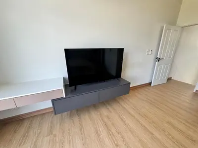 a living room with a flat screen tv on a entertainment center at Modern townhome in Phuket in Ban Phak Chit