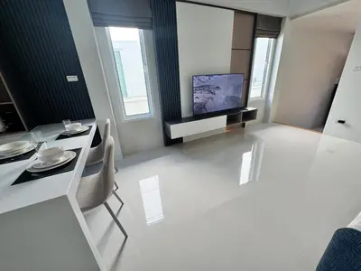 a living room with a television and a table and chairs at Modern townhome in Phuket in Ban Phak Chit