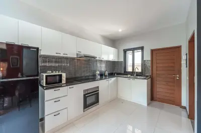 a kitchen with white cabinets and a sink and a microwave at 3 BR Pool Villa Salika near Rawai Beach in Ban Saiyuan (1)