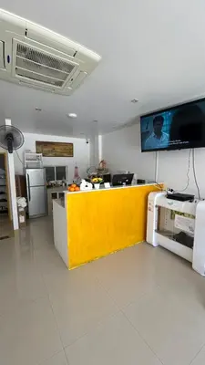 a kitchen with a yellow counter and a tv on the wall at rawai cozy hostel in Rawai Beach