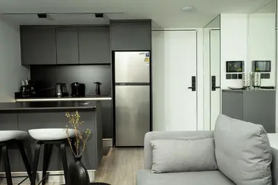 a kitchen with a couch and a refrigerator at Harmony Condominium Phuket in Ban Saiyuan (1)