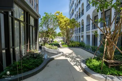 a sidewalk in front of a building with trees at Harmony Condominium Phuket in Ban Saiyuan (1)