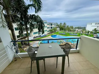 a balcony with a table and chairs and a swimming pool at One BR 24 in Ban Karon