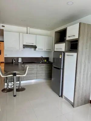 a kitchen with a table and a refrigerator at One BR 24 in Ban Karon
