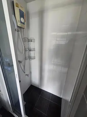 a bathroom with a shower and a black tile floor at Dcondo in Ban Kathu