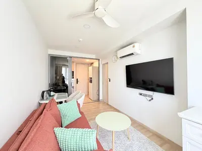 a living room with a couch and a tv on a wall at Skypark 4th floor Mountain View terrace in Laguna Phuket