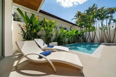 a patio with two chairs and a swimming pool at 2BR Pool Villa Kate - KA Villas near Rawai Beach in Rawai Beach