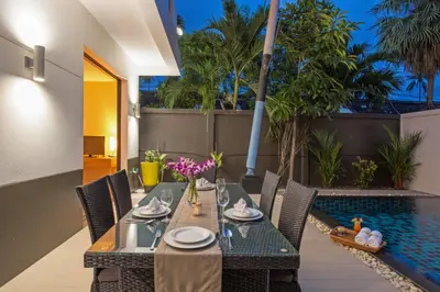 a dining room with a table and chairs next to a pool at 3 BR Pool Villa Kloua near Chalong Temple in Ban Na Bon