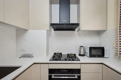 a white kitchen with a stove and a microwave at Townhouse Laguna Park 3 bedrooms in Laguna Phuket