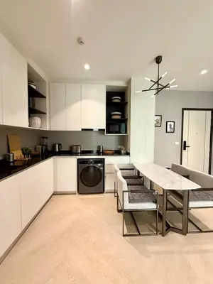 a kitchen with white cabinets and a table with chairs at Bali Essence, The Title BangTao in Bang Tao Beach