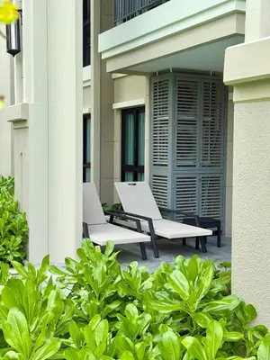 two white chairs sitting on a patio next to a building at Bali Essence, The Title BangTao in Bang Tao Beach