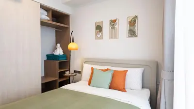 a bedroom with a bed with orange and green pillows at Natural Harmony - SkyPark Celeste in Laguna Phuket