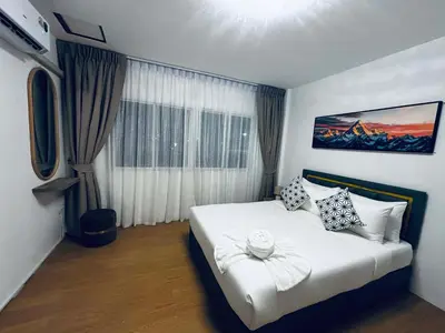 a bedroom with a white bed with a large window at Phuket gateway inn in Ban Kathu