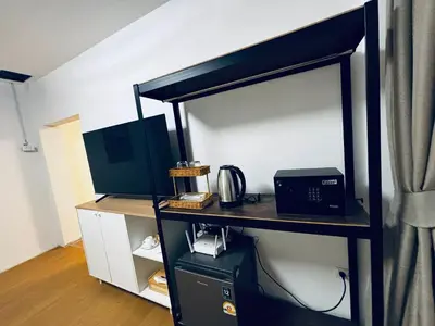 a room with a desk with a microwave and a printer at Phuket gateway inn in Ban Kathu