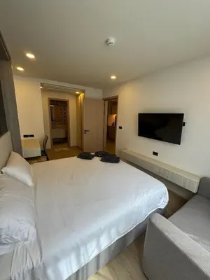a bedroom with a large white bed and a flat screen tv at Пляж Бангтао Резиденция Ozon in Laguna Phuket