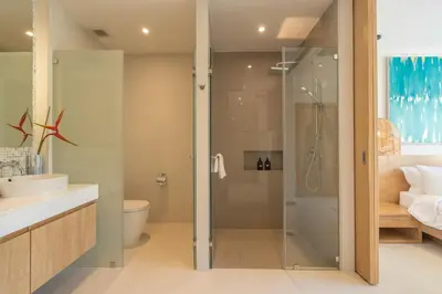 a bathroom with a shower and a toilet and a sink at The Sandstone Villa at Trichada Breeze in Laguna Phuket