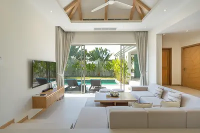 a living room with a couch and a tv at The Sandstone Villa at Trichada Breeze in Laguna Phuket