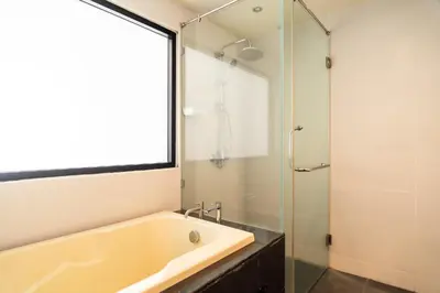 a bathroom with a tub and a glass shower at Patong hillside Condo with pool, bar, parking in Patong Beach