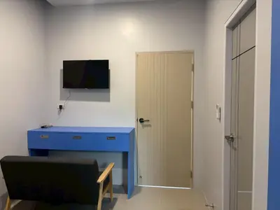 a room with a blue desk and a tv on a wall at Tiny house bangtao in Ban Thalat Choeng Thale