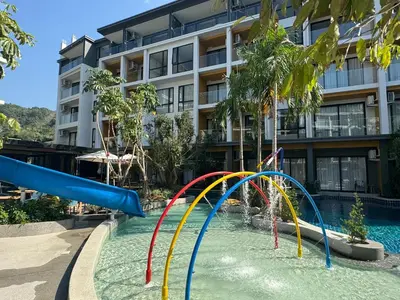 a pool with a water slide in front of a building at Wyndham apartment Naithon in Nai Thon Beach