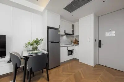 a kitchen with a table with chairs and a refrigerator at Tinos 1BR Suite at Kora Beach Resort in Layan Beach