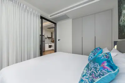 a bedroom with a white bed with blue pillows at Tinos 1BR Suite at Kora Beach Resort in Layan Beach