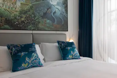 a bedroom with a bed with blue pillows and a painting at Tinos 1BR Suite at Kora Beach Resort in Layan Beach