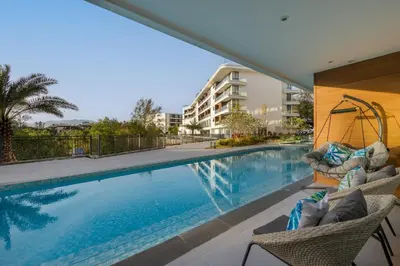 a swimming pool with two chairs next to a building at Lamia 1BR Suite at Kora Beach Resort in Layan Beach