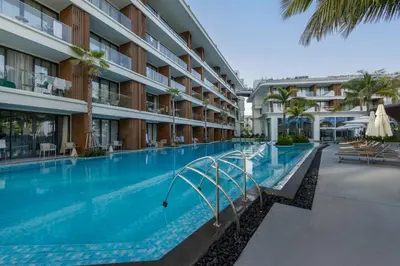 an empty swimming pool in a hotel with palm trees at Lamia 1BR Suite at Kora Beach Resort in Layan Beach