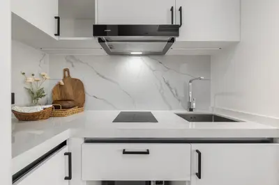 a white kitchen with a sink and a microwave at Lamia 1BR Suite at Kora Beach Resort in Layan Beach