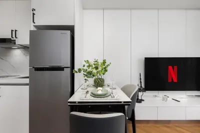 a kitchen with a refrigerator and a table with flowers on it at Lamia 1BR Suite at Kora Beach Resort in Layan Beach