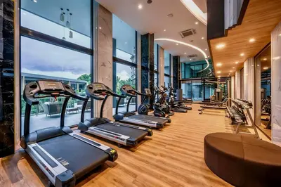 a row of treadmills in a gym with windows at Mida Grande Surin Private Suites in Ban Lum Fuang