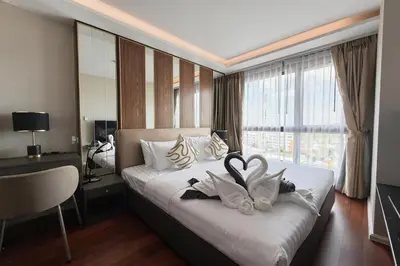 a hotel room with a bed with towels on it at Mida Grande Surin Private Suites in Ban Lum Fuang