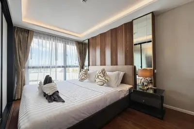 a bedroom with a large bed with a large window at Mida Grande Surin Private Suites in Ban Lum Fuang