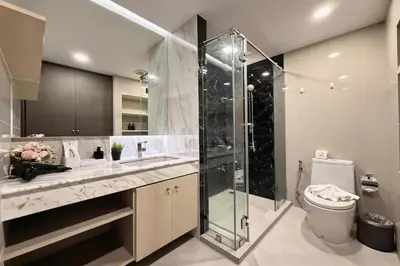 a bathroom with a glass shower and a toilet at Mida Grande Surin Private Suites in Ban Lum Fuang
