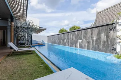 a swimming pool with a chair next to a wall at PRAIA Residence 5BR - Bangtao in Ban Pak Lak