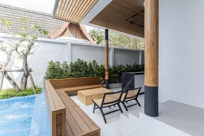 a patio with a table and chairs next to a pool at PRAIA Residence 5BR - Bangtao in Ban Pak Lak
