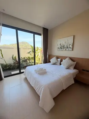 a bedroom with a large white bed with a large window at Chareen Pool Villa in Ban Khlong Haeng