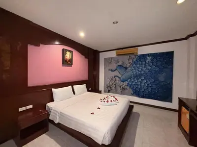 a bedroom with a white bed with a painting on the wall at Nova Inn in Patong Beach