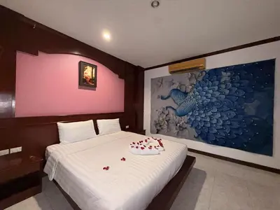 a bedroom with a white bed and a painting at Nova Inn in Patong Beach