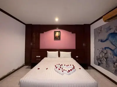 a bedroom with a white bed with a heart shaped pillow at Nova Inn in Patong Beach