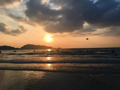 a sunset on the beach with people flying a kite at GO INN Patong - โกอินน์ ป่าตอง in Patong Beach