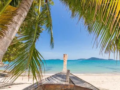 a boat sitting on the beach under a palm tree at Large 1 Bedroom Apt Sleeps 4, Close to Beach - RM 1 in Ban Lum Fuang